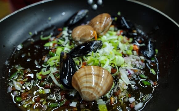 Frische Meeresfrüchte mit Frühlingszwiebeln in einer Pfanne